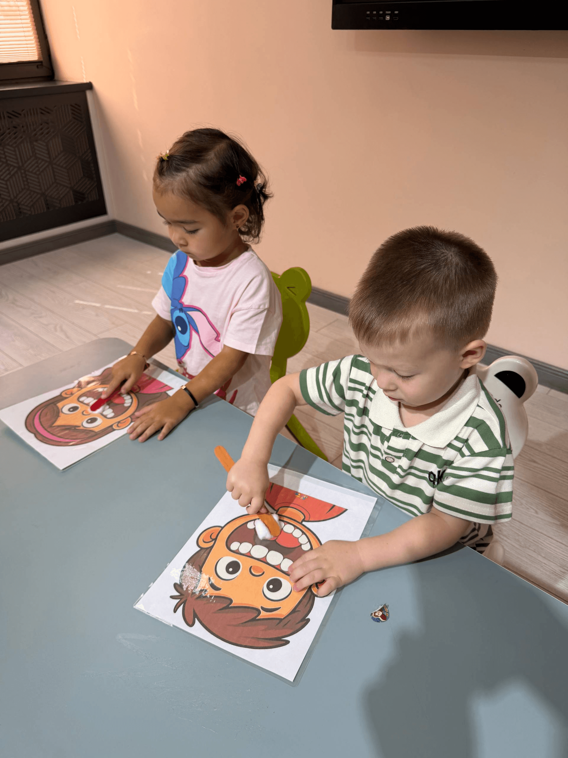 A girl and boy painting a craft template together at Little Britain Daycare