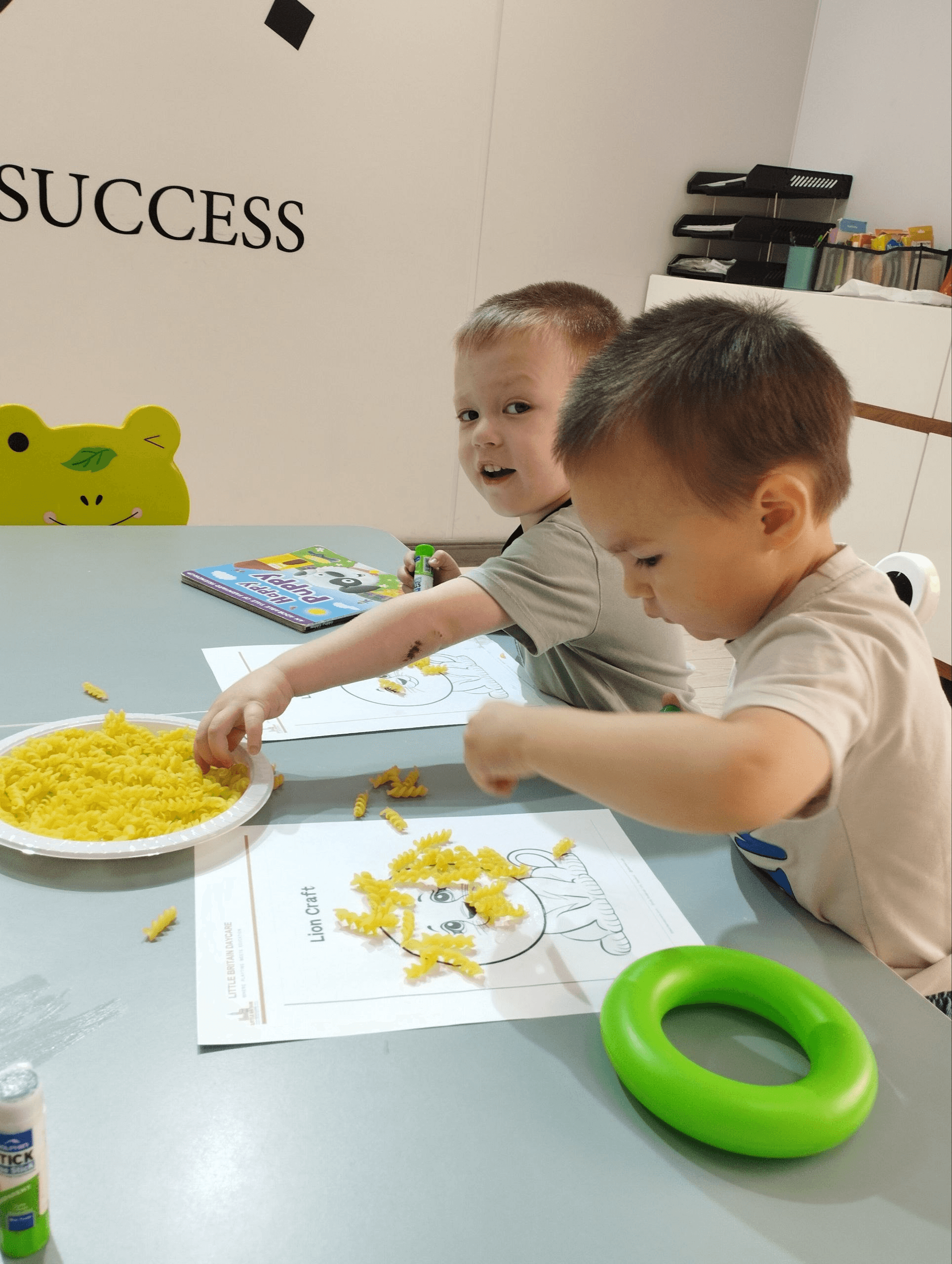 Children gluing pasta to make a lion craft at Little Britain Daycare
