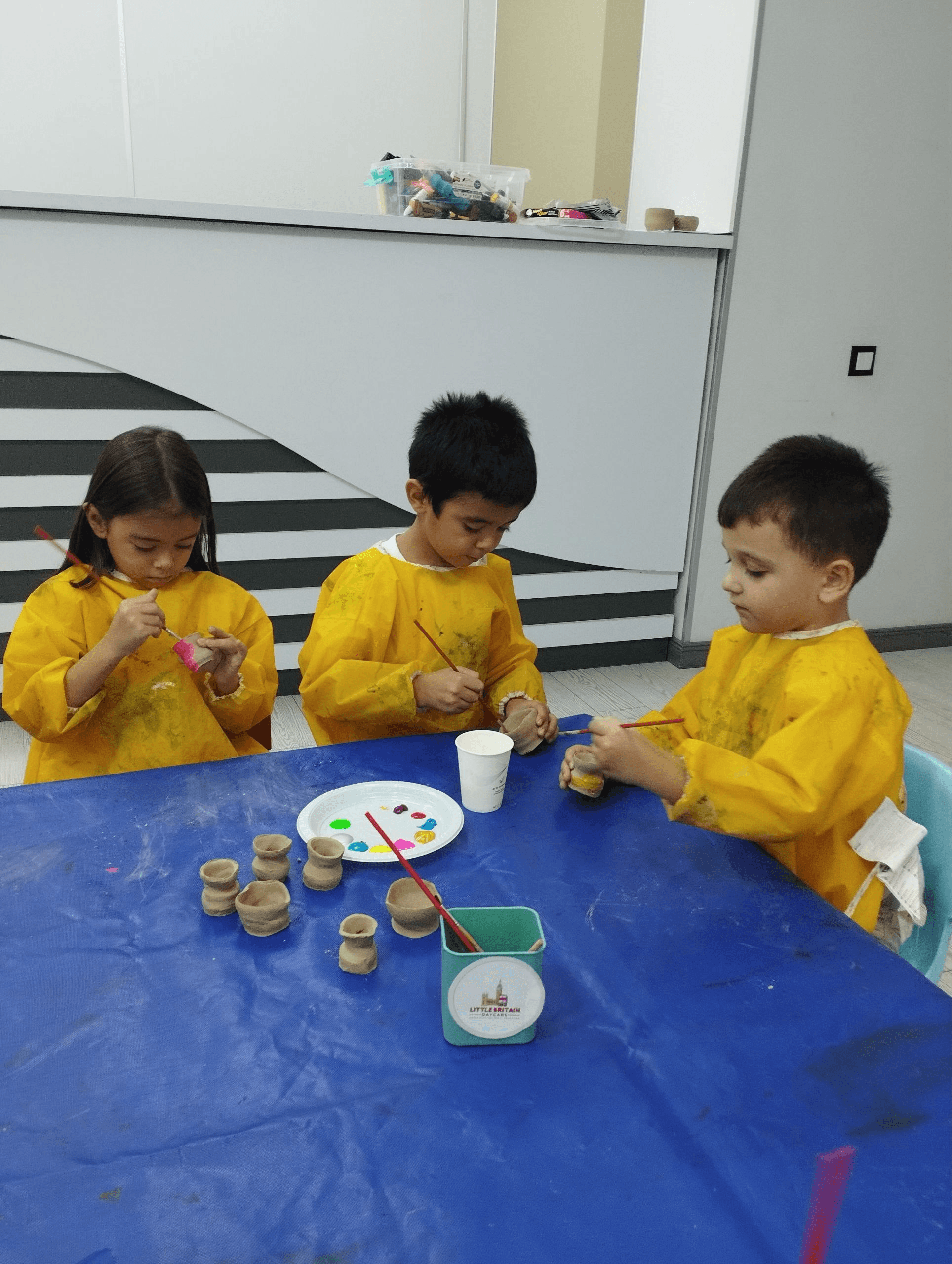 Children painting handmade clay pots at Little Britain Daycare